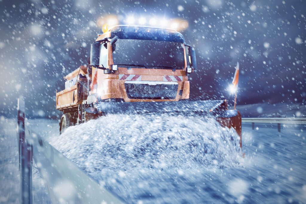 Moving snowplow truck pushing snow to the side of the road.