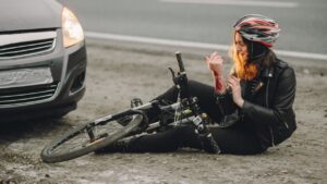 an injured woman due to bicycle accident in front of a car