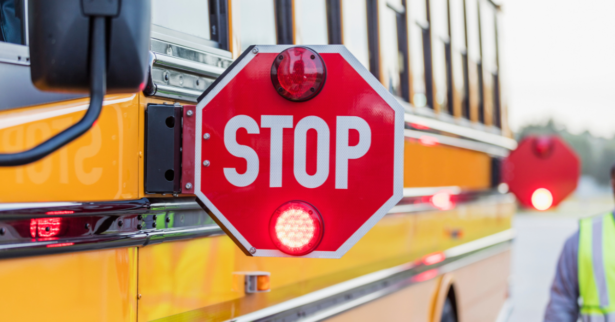 School bus stop sign extended with flashing lights for Christensen Law blog on Michigan school bus traffic laws.