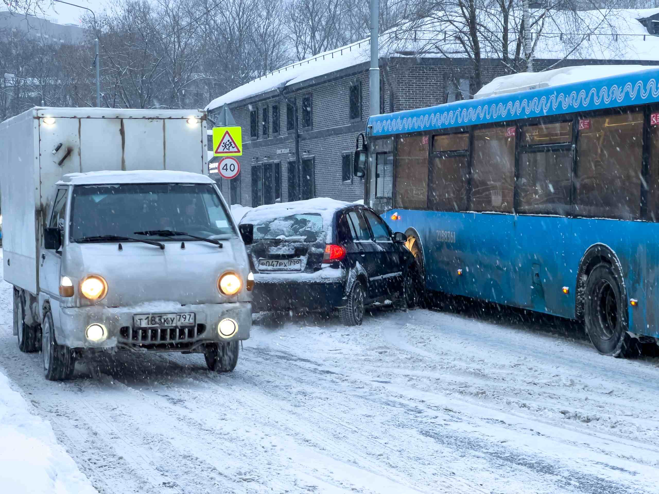 A car collides with a blue transit bus on a snowy road investigated by Detroit bus accident lawyers.