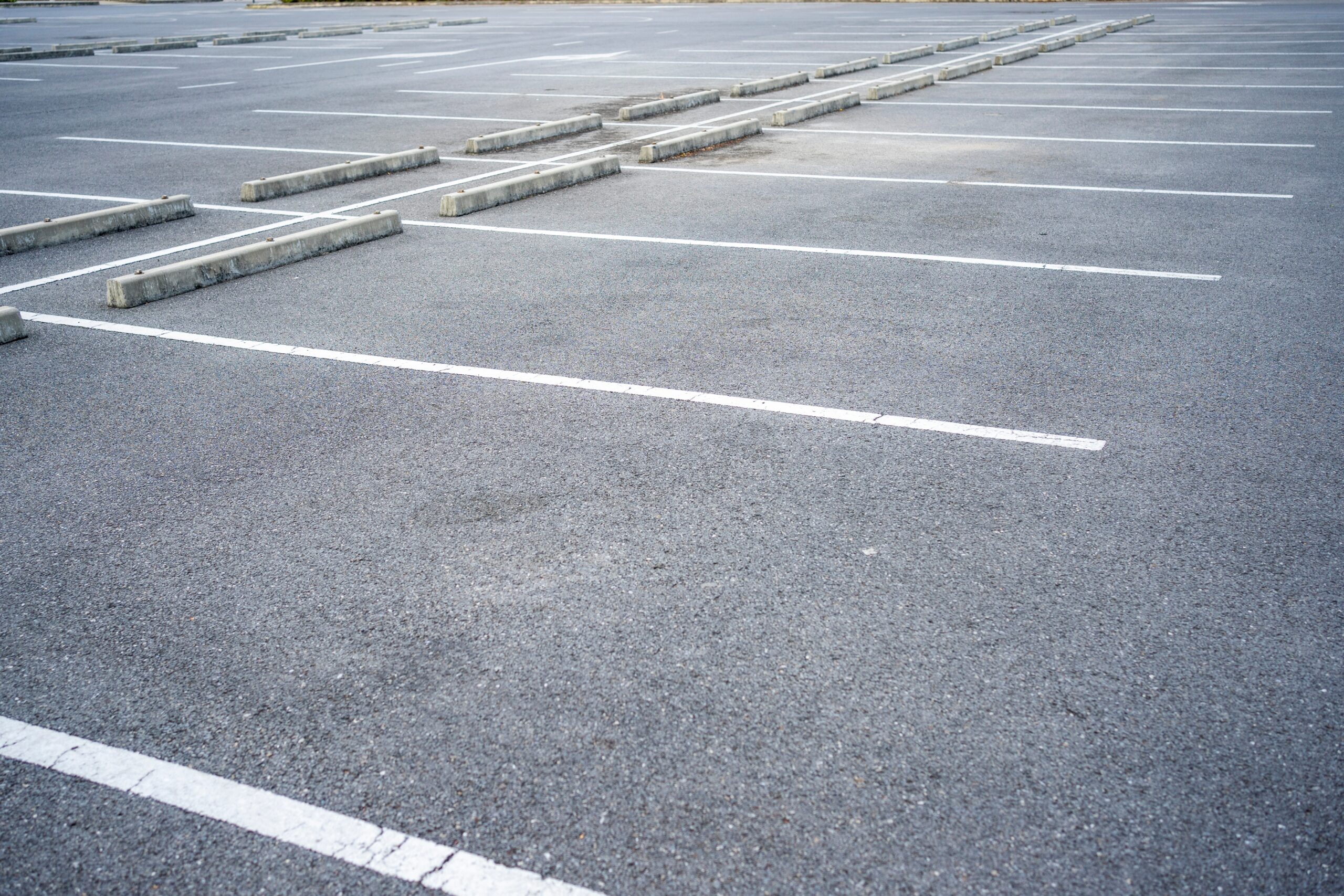 Empty asphalt lot with painted stalls served by a Detroit, MI parking lot accident lawyer.