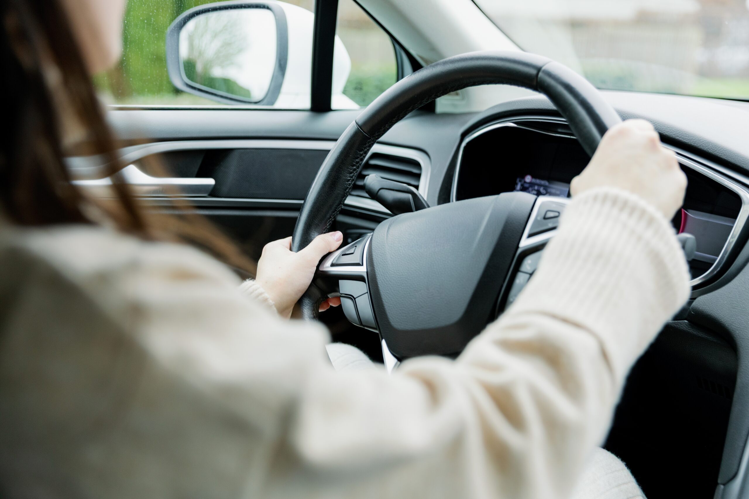 Woman holding the steering wheel inside a modern car.