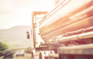 Large fuel tanker truck driving along a sunny highway.