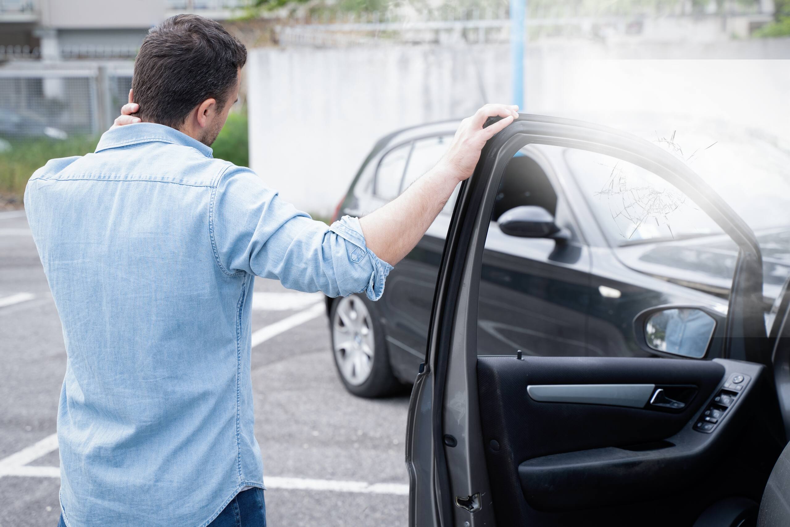 Injured man holding his neck while exiting a vehicle represented by a Michigan reckless driving accident lawyer.